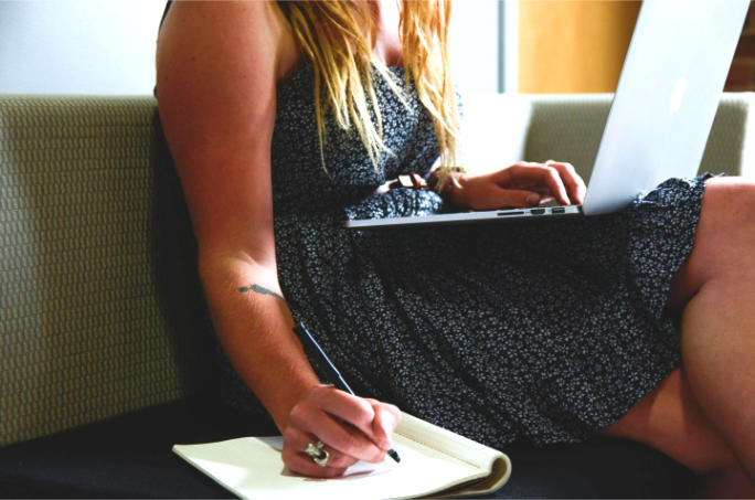 Eine Frau macht sich am Laptop Notizen während des Online-Kurses